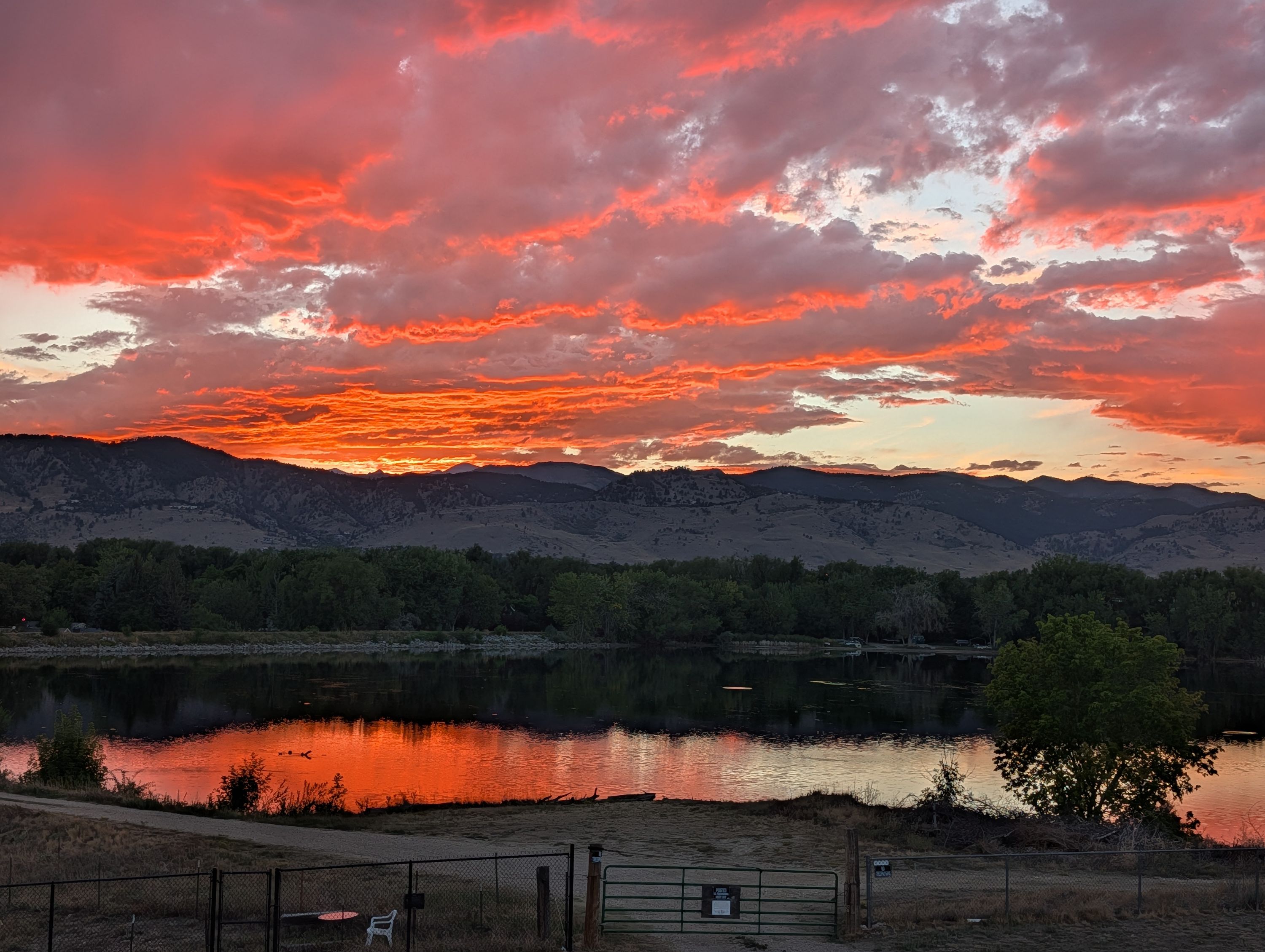 Sunset burning red and orange over the Front Range, reflected in the lake below.