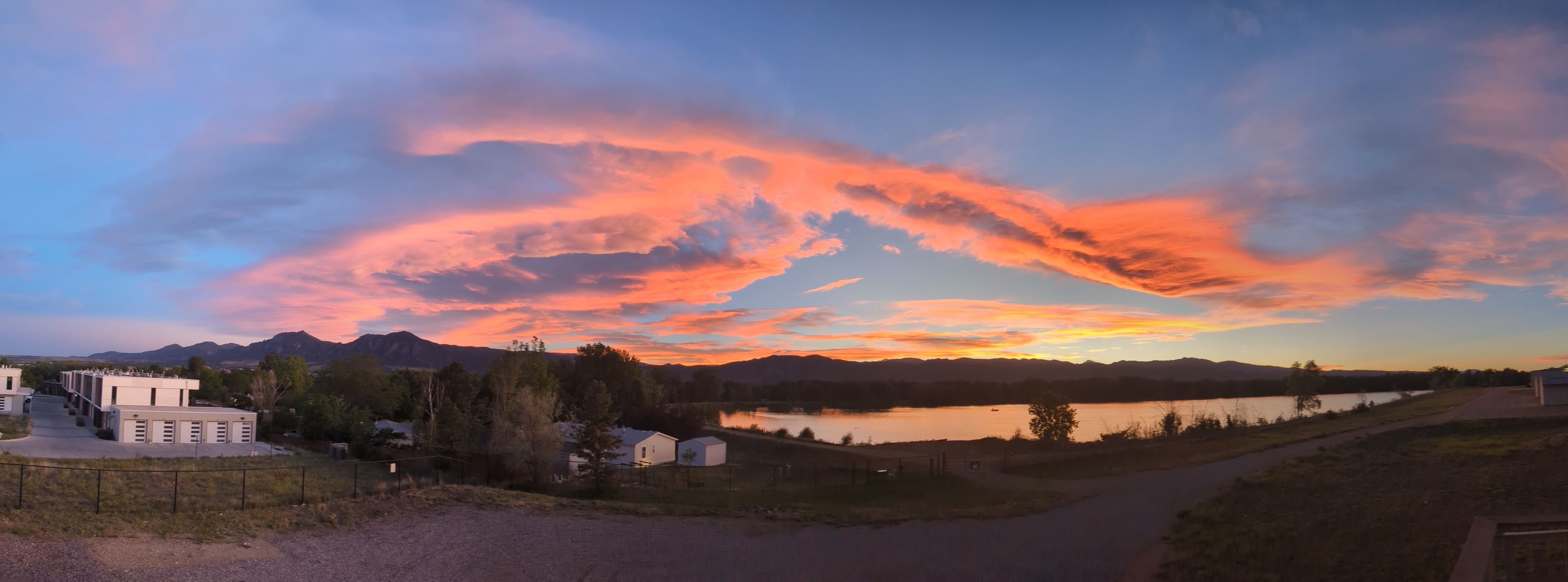Wide panorama at sunset from the balcony: the full Front Range along the horizon with the lake below.