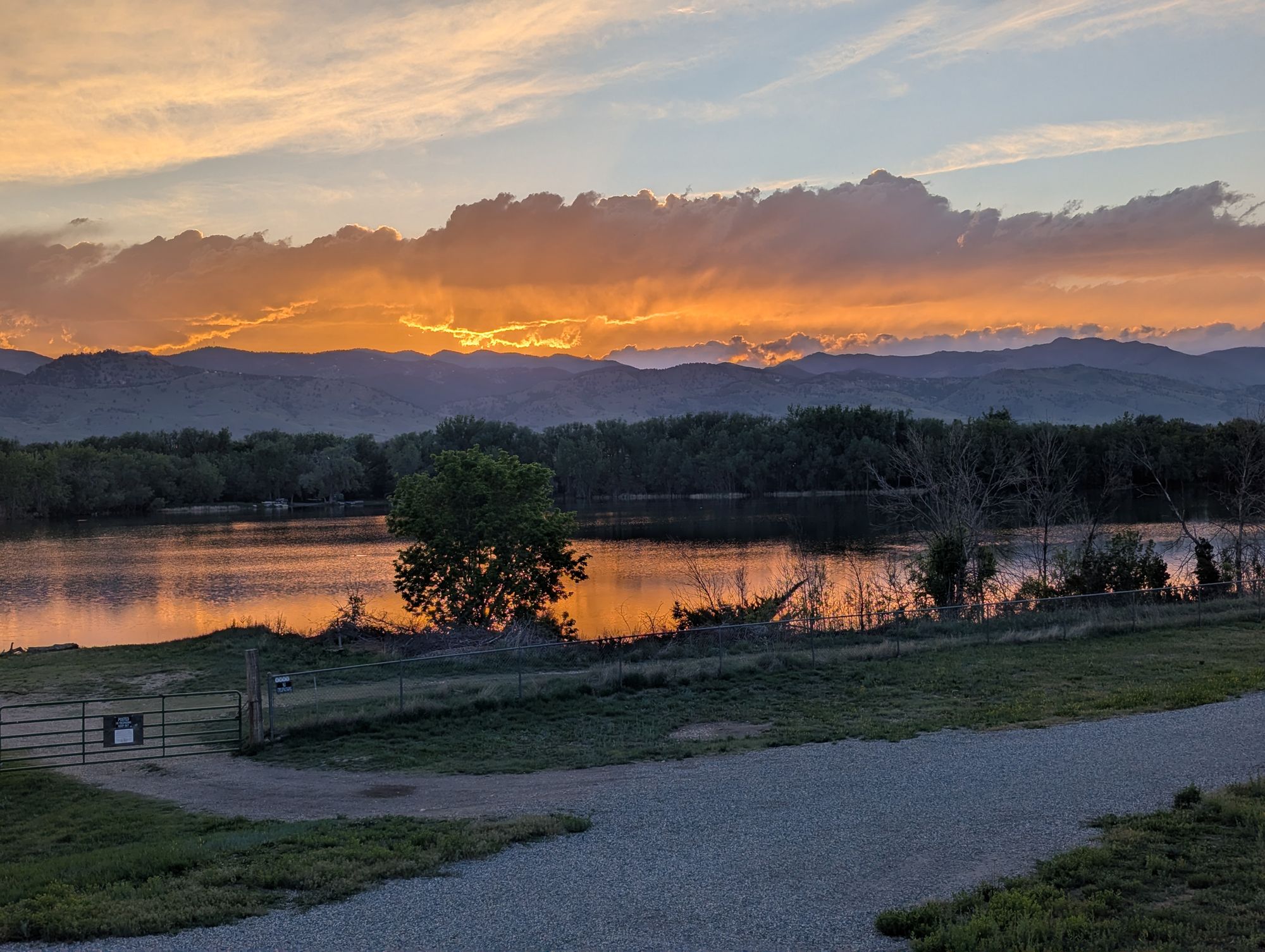 Sun setting behind layered ridgelines with the lake catching the light.